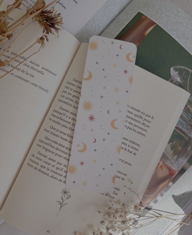 Marque-page céleste soleils et étoiles glissé dans un livre ouvert