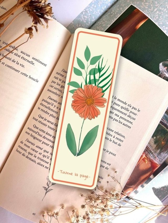 Marque-page fleur terracotta « Tourne la page » glissé dans un livre ouvert