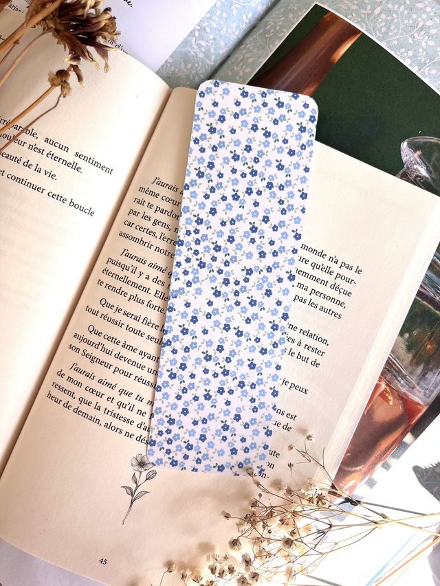 Marque-page petites fleurs bleues glissé dans un livre ouvert