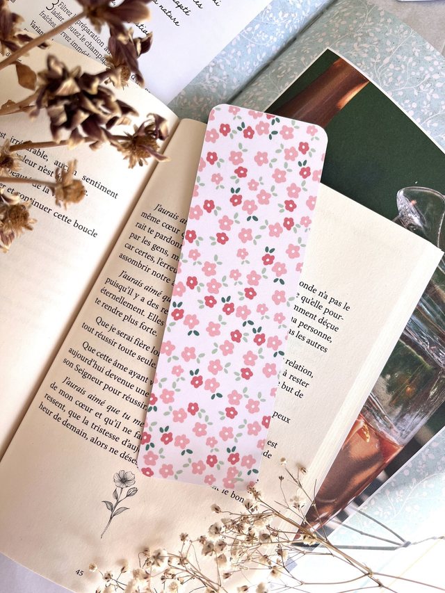 Marque-page petites fleurs roses glissé dans un livre ouvert