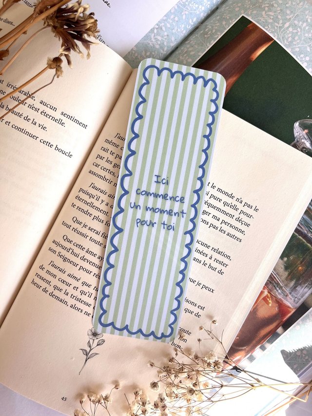 Marque-page rayures vert sauge et feston bleu glissé dans un livre ouvert