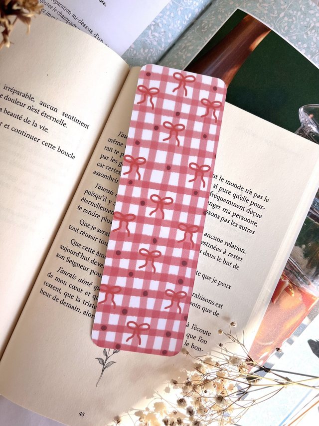 Marque-page vichy rose et nœuds rouges glissé dans un livre ouvert