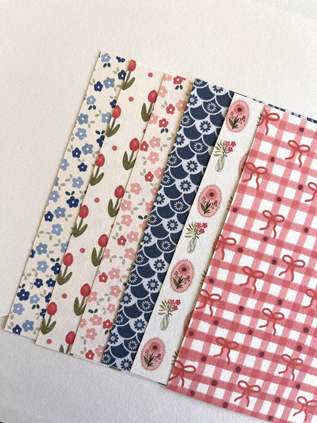 Feuilles de papier scrapbooking florales et géométriques disposées en éventail