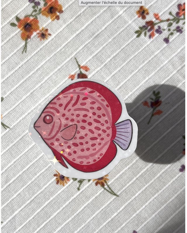 Sticker poisson tropical rose pailleté posé sur une nappe à fleurs